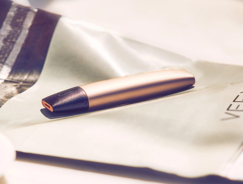 A gold VEEV vape device on a wooden table
