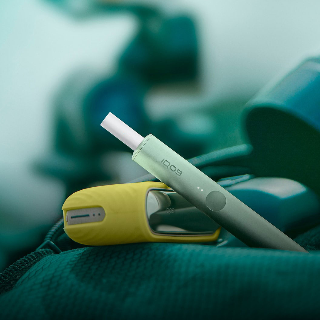 A Moss Green IQOS ILUMA Holder and a Pocket Charger covered with a sleeve.