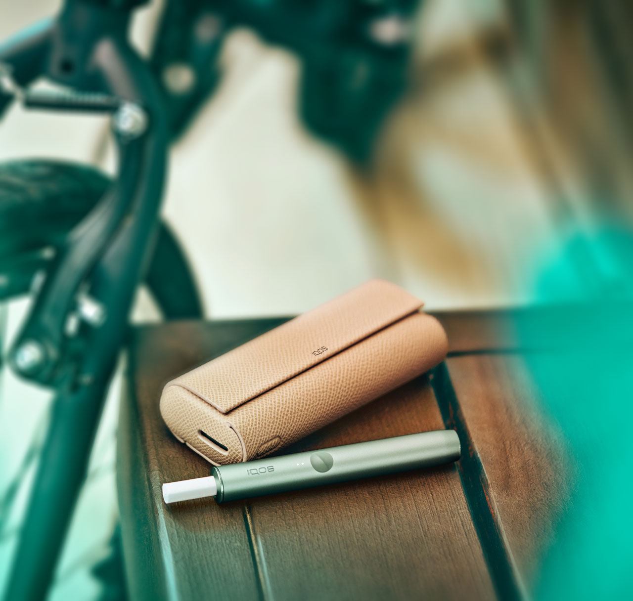 A Jade Green IQOS ILUMA PRIME Holder and Pocket Charger in a full wrap on a table.